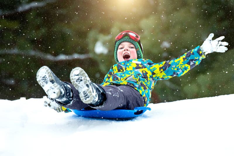 Jongen het sledding in een sneeuw bos Openlucht de winterpret voor Kerstmisvakantie stock foto's Jongen het sledding in een sneeuw bos Openlucht de winterpret voor Kerstmisvakantie stock foto's