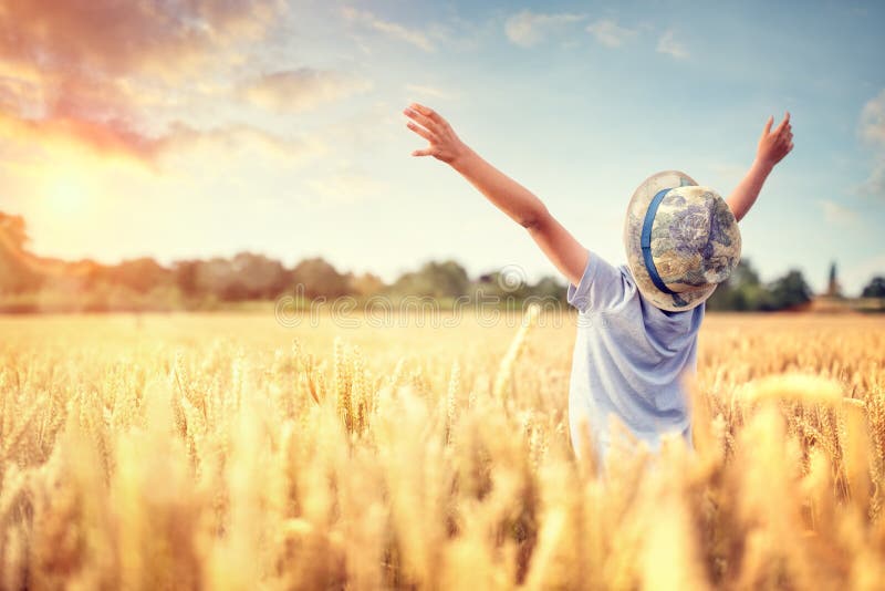 Jongen met opgeheven wapens op tarwegebied in de zomer het letten op zonsondergang royalty-vrije stock afbeelding Jongen met opgeheven wapens op tarwegebied in de zomer het letten op zonsondergang royalty-vrije stock afbeelding