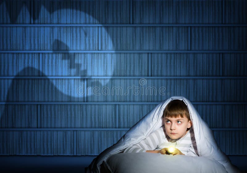 Image of a boy under the covers with a flashlight the night afraid of ghosts. Image of a boy under the covers with a flashlight the night afraid of ghosts