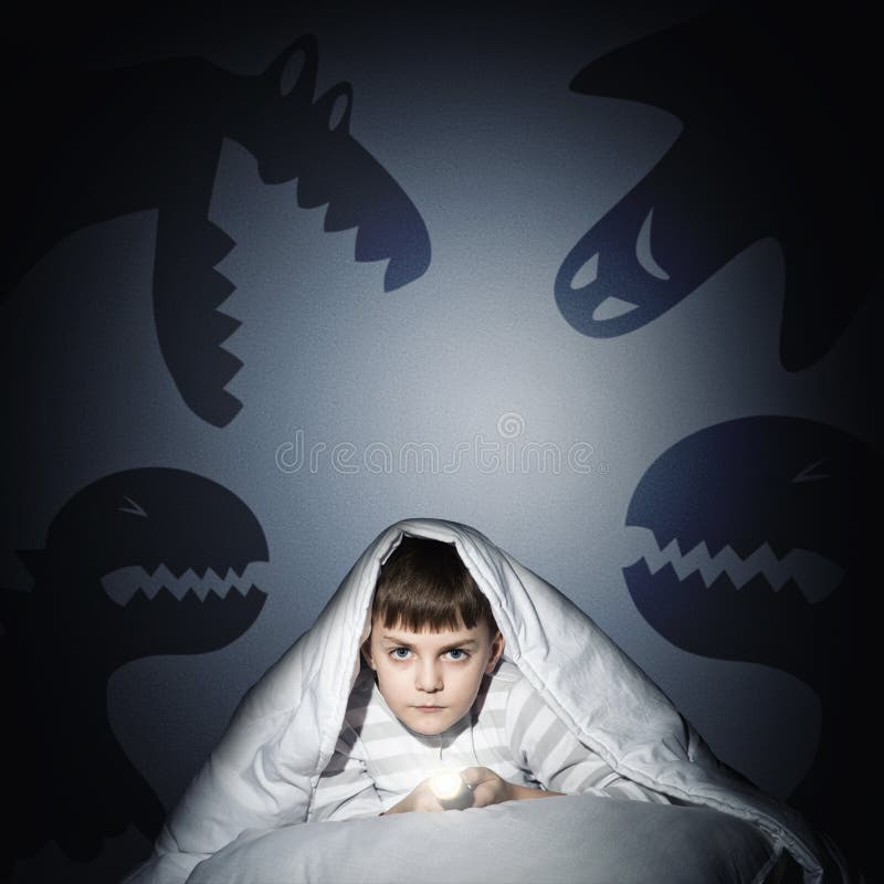 Image of a boy under the covers with a flashlight the night afraid of ghosts. Image of a boy under the covers with a flashlight the night afraid of ghosts