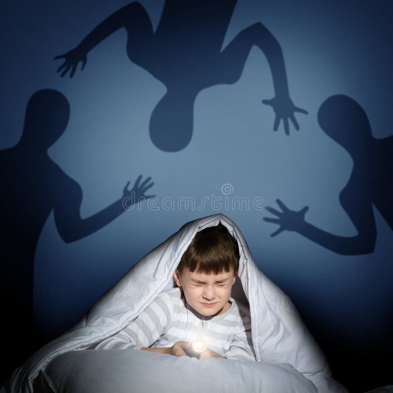 Image of a boy under the covers with a flashlight the night afraid of ghosts. Image of a boy under the covers with a flashlight the night afraid of ghosts