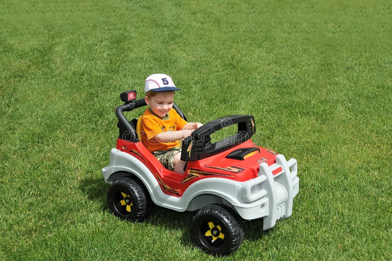 Jongen in stuk speelgoed auto op gras stock foto Jongen in stuk speelgoed auto op gras stock foto