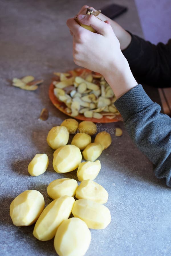 Jongenshanden die aardappels pellen royalty-vrije stock fotografie Jongenshanden die aardappels pellen royalty-vrije stock fotografie