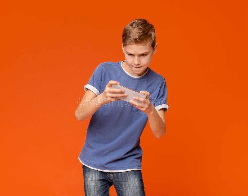 Jongensholding cellphone en het spelen videospelletjes royalty-vrije stock foto's Jongensholding cellphone en het spelen videospelletjes royalty-vrije stock foto's