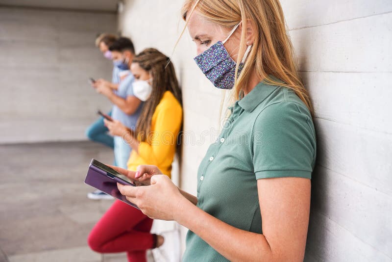 Jongeren dragen gezichtsveiligheidsmaskers met mobiele telefoons terwijl ze de sociale afstand bewaren tijdens de uitbraak van het