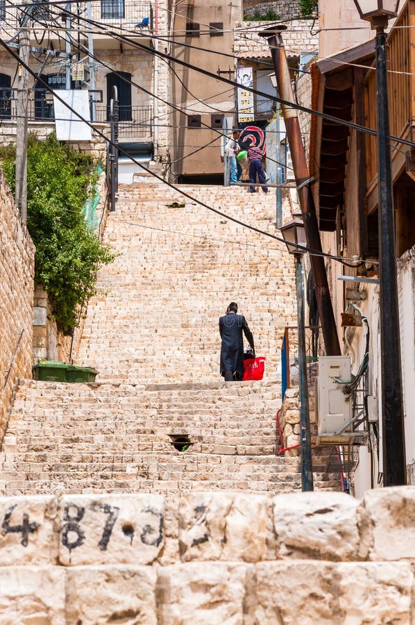 Joodse orthodox met rode zak gaat de treden in Oude Stad in Safed, Israël uit royalty-vrije stock foto's Joodse orthodox met rode zak gaat de treden in Oude Stad in Safed, Israël uit royalty-vrije stock foto's