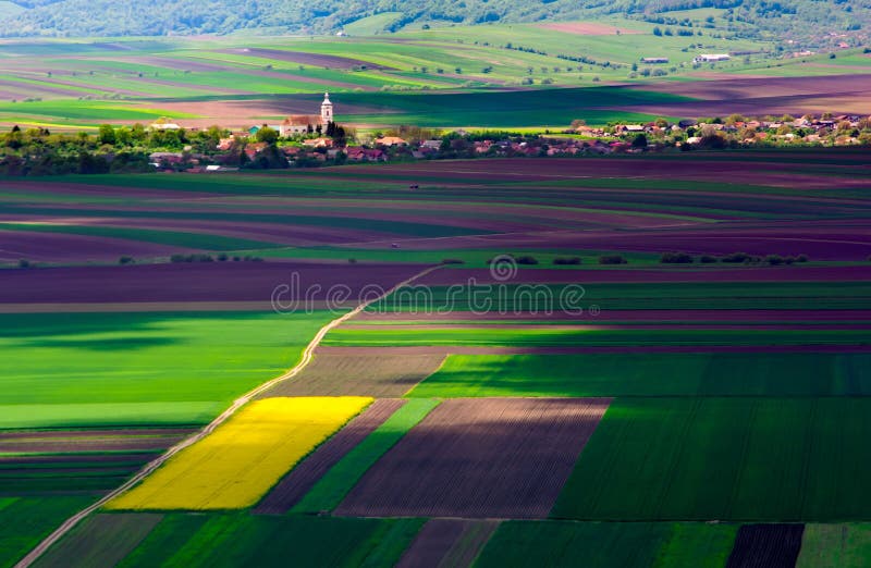 Jordbruks- fält på en sommardag med den Transylvania byn royaltyfri foto Jordbruks- fält på en sommardag med den Transylvania byn royaltyfri foto