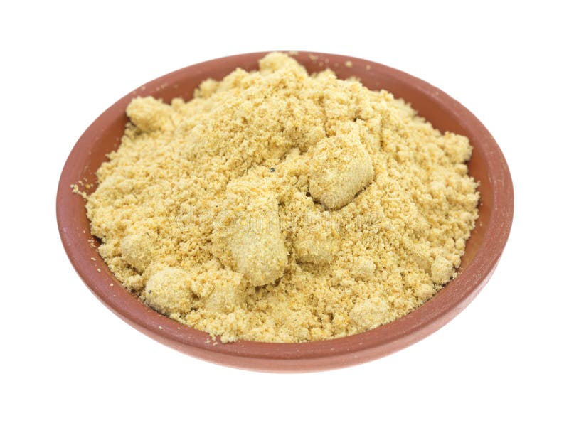 A portion of dried ground mustard in a small red clay bowl on a white background. A portion of dried ground mustard in a small red clay bowl on a white background.