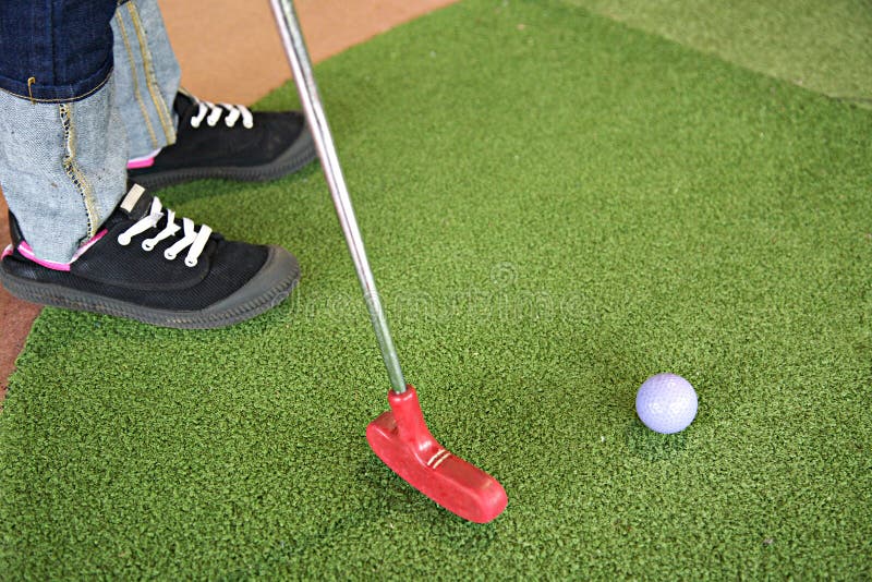 Jouer au mini golf avec le putter rouge image stock Jouer au mini golf avec le putter rouge image stock