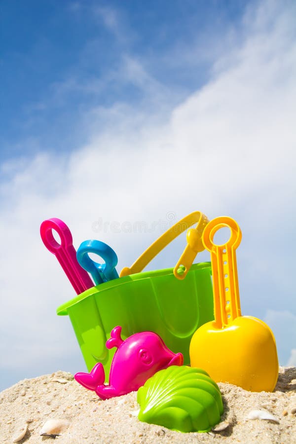 Child's bucket, spade and other toys on tropical beach against blue sky. Child's bucket, spade and other toys on tropical beach against blue sky