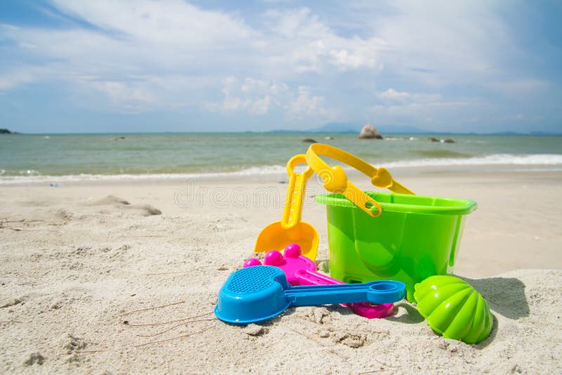 Child's bucket, spade and other toys on tropical beach against blue sky. Child's bucket, spade and other toys on tropical beach against blue sky