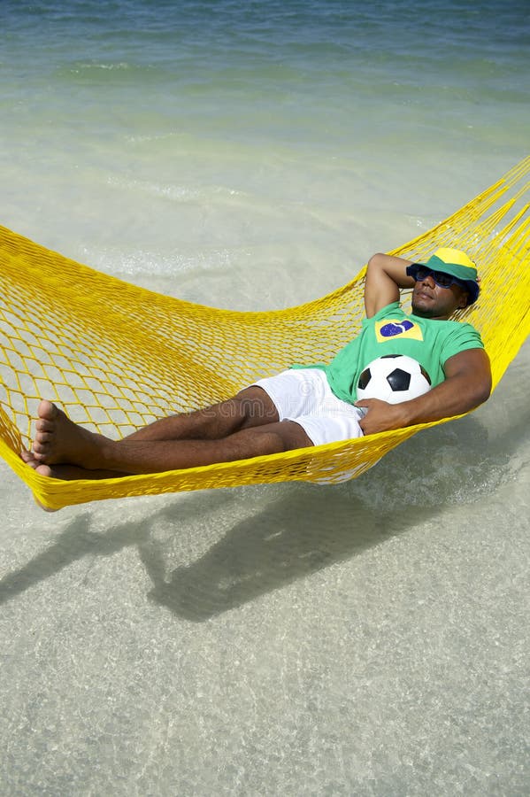 Joueur de football brésilien détendant dans l'hamac de plage photographie stock Joueur de football brésilien détendant dans l'hamac de plage photographie stock