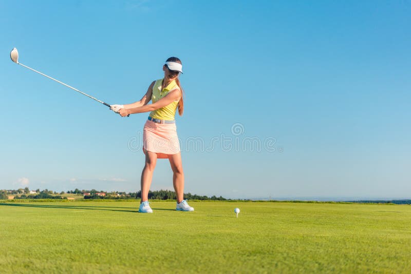 Joueur de golf féminin professionnel souriant tout en balançant un club de conducteur photos libres de droits Joueur de golf féminin professionnel souriant tout en balançant un club de conducteur photos libres de droits