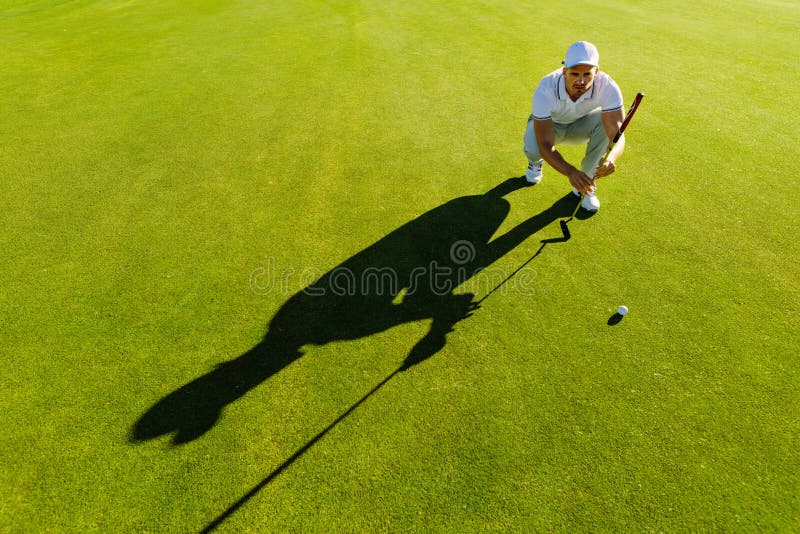Joueur de golf visant le tir avec le club sur le cours photo stock Joueur de golf visant le tir avec le club sur le cours photo stock