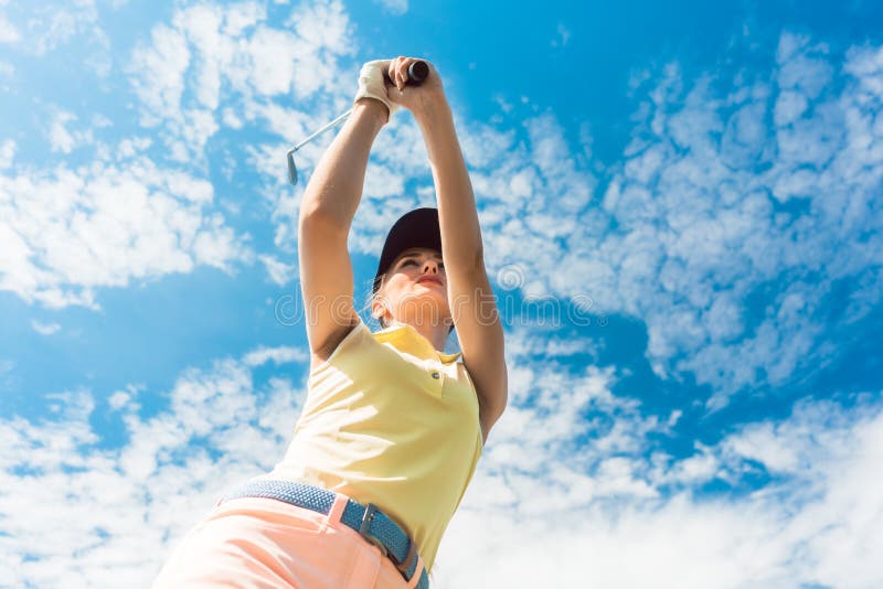 Joueur professionnel féminin supportant le club de fer tout en jouant le golf photographie stock Joueur professionnel féminin supportant le club de fer tout en jouant le golf photographie stock
