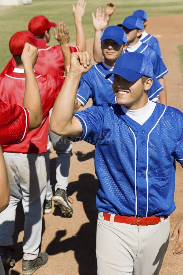 Players giving a high-five to each other while walking on field. Players giving a high-five to each other while walking on field