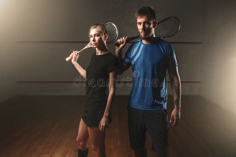 Joueurs masculins et féminins de jeu de courge avec des raquettes photo stock Joueurs masculins et féminins de jeu de courge avec des raquettes photo stock