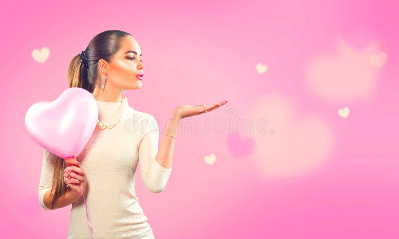 Jour du `s de Valentine Fille de beauté avec le ballon à air en forme de coeur rose dirigeant la main