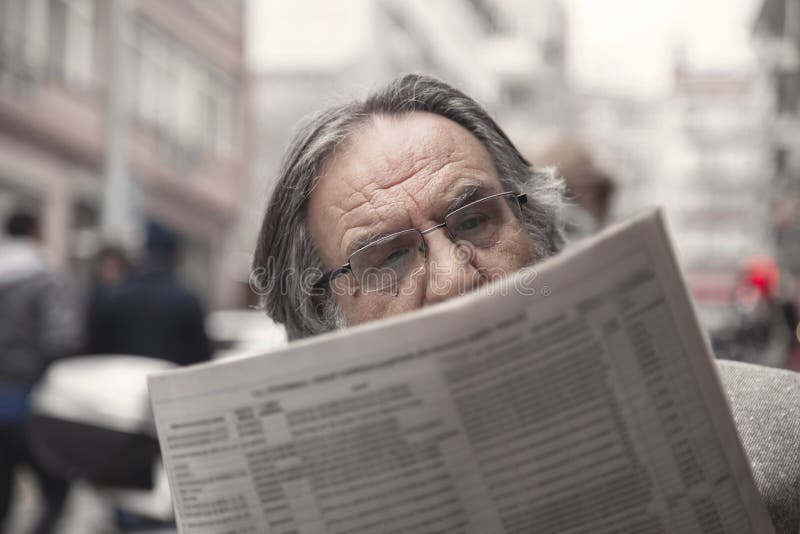 Journal de lecture d'homme supérieur dedans dehors photographie stock libre de droits Journal de lecture d'homme supérieur dedans dehors photographie stock libre de droits