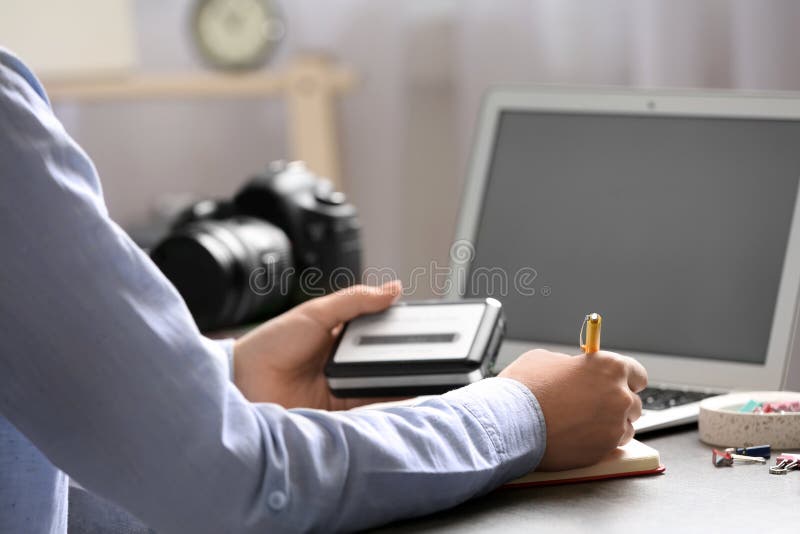 Journalist with Voice Recorder Working at Table in Office Stock Image
