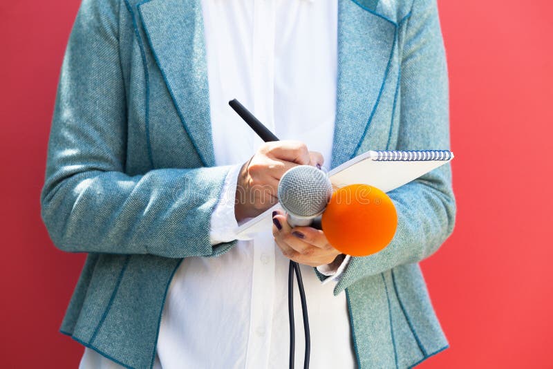 Journaliste f?minin ? la conf?rence de presse, ?crivant des notes, tenant le microphone photo stock Journaliste f?minin ? la conf?rence de presse, ?crivant des notes, tenant le microphone photo stock