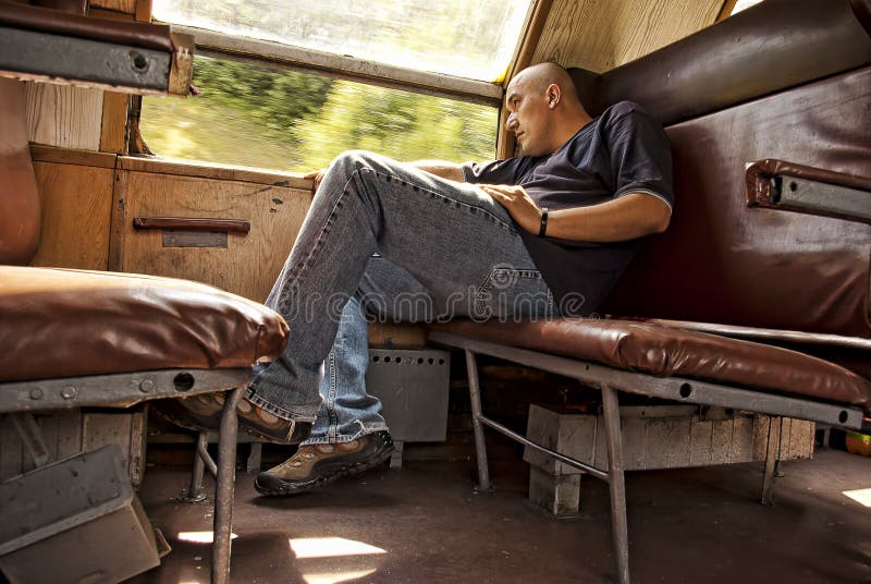 Mladý muž cestuje na starý vlak na balkáne, pri pohľade z okna.