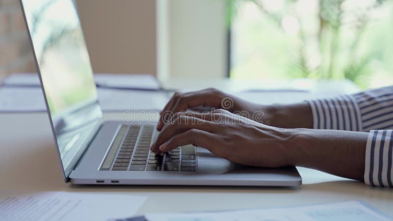 Jovem africano e negra mãos digitando no teclado do laptop.