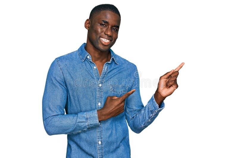 Young african american man wearing casual clothes smiling and looking at the camera pointing with two hands and fingers to the side. Young african american man wearing casual clothes smiling and looking at the camera pointing with two hands and fingers to the side