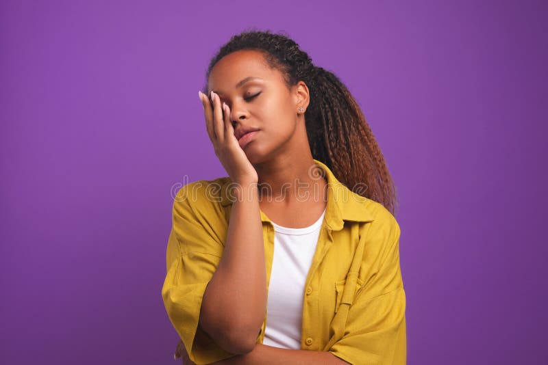 Só o café pode me refrescar. mulher afro-americana sonolenta e cansada  cobre metade do rosto com a palma da mão, tem expressão triste, fecha os  olhos, carrega um copo descartável de bebida com cafeína, continua  trabalhando.