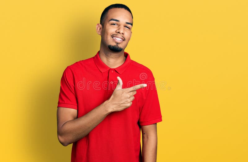 Young african american man wearing casual polo smiling cheerful pointing with hand and finger up to the side. Young african american man wearing casual polo smiling cheerful pointing with hand and finger up to the side
