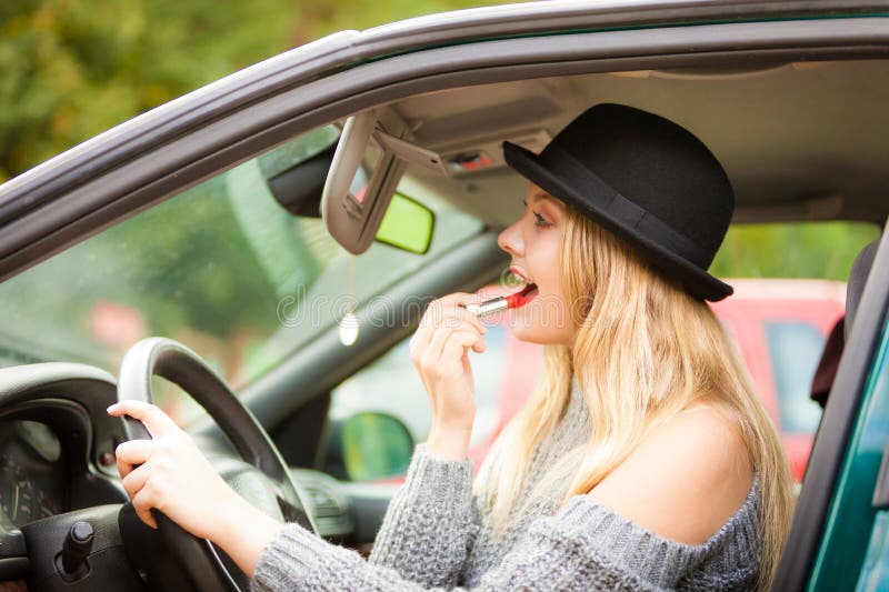Jovem aplicando batom no carro foto de stock royalty free