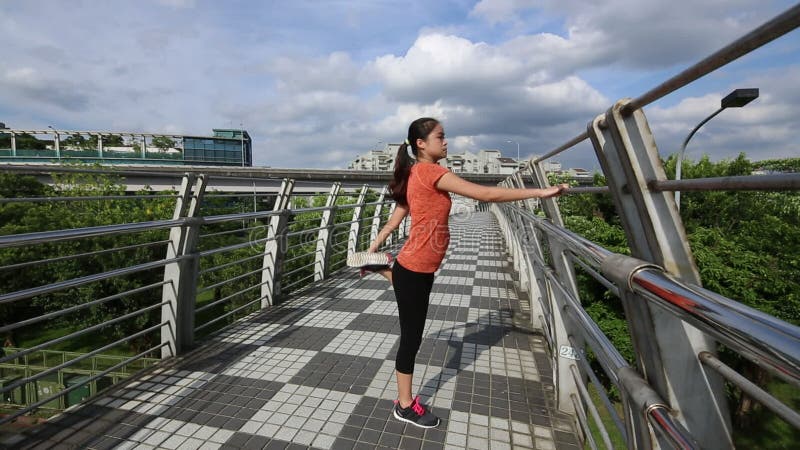 Jovem asiática que se estende antes de uma corrida numa ponte na cidade de taiwan