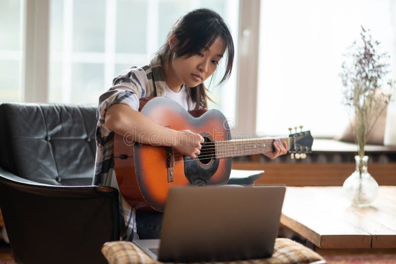 Jovem asiática tendo uma aula online tocando violão imagens de stock royalty free