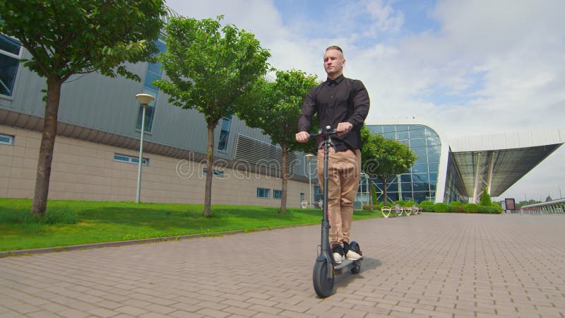 Jovem bem-sucedido dirige uma moto elétrica perto do centro de negócios. jovens numa scooter elétrica.