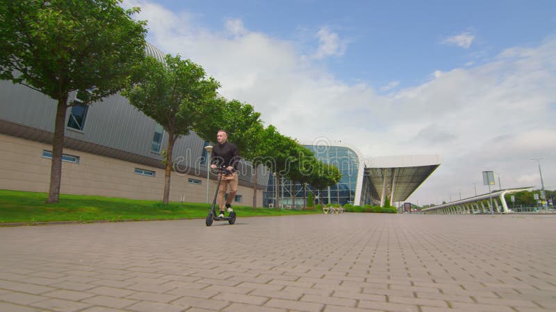 Jovem bem-sucedido dirige uma moto elétrica perto do centro de negócios. jovens numa scooter elétrica.