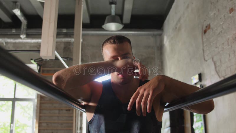 Jovem cansado em bares paralelos no ginásio