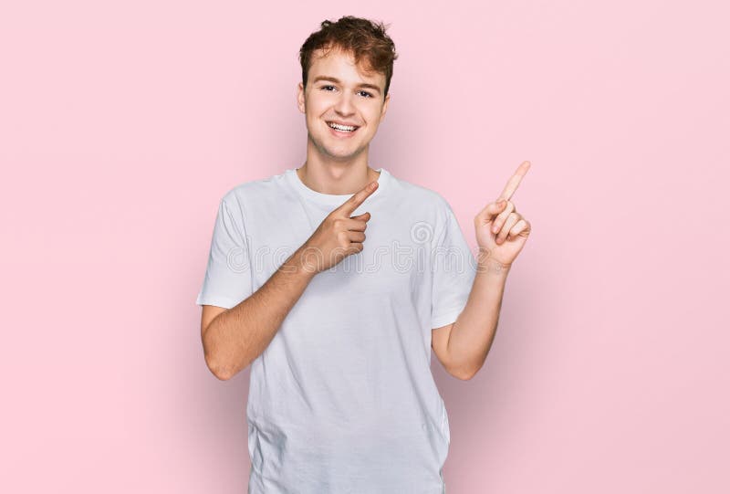 Young caucasian man wearing casual white t shirt smiling and looking at the camera pointing with two hands and fingers to the side. Young caucasian man wearing casual white t shirt smiling and looking at the camera pointing with two hands and fingers to the side