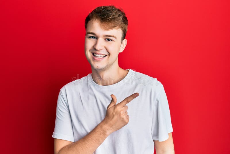 Young caucasian man wearing casual white t shirt smiling cheerful pointing with hand and finger up to the side. Young caucasian man wearing casual white t shirt smiling cheerful pointing with hand and finger up to the side