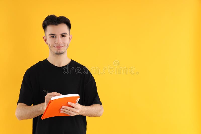 Jovem com caderno e caneta de fundo amarelo fotos de stock