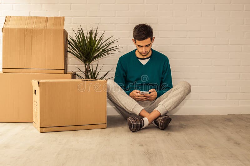 Jovem com caixas móveis no apartamento imagens de stock