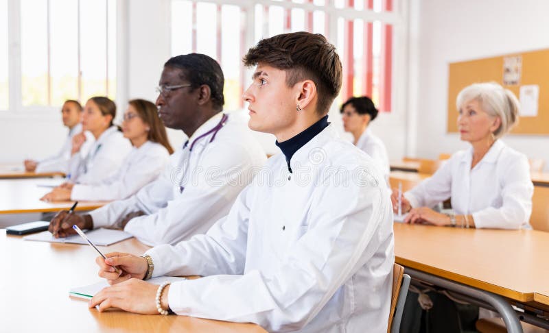 Jovem de casaco branco que frequenta palestra na universidade médica imagens de stock royalty free
