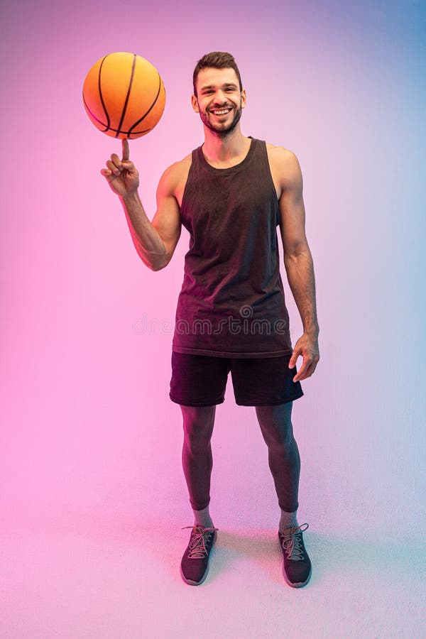 Jovem desportista jogando bola de basquete no dedo
