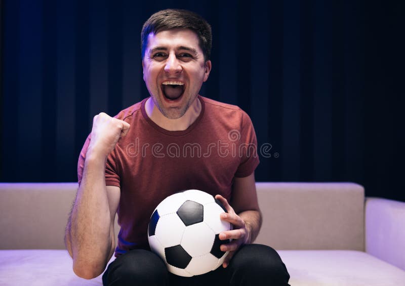 O Jogador De Futebol Dos Anos 30 Anima-se a Apoiar O Time Favorito Que  Segura Bola De Futebol Na Sala Escura. Emoções Das Pessoas Imagem de Stock  - Imagem de equipe, emocional