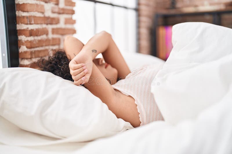 Jovem mulher do Médio Oriente stressada deitada na cama no quarto fotografia de stock royalty free