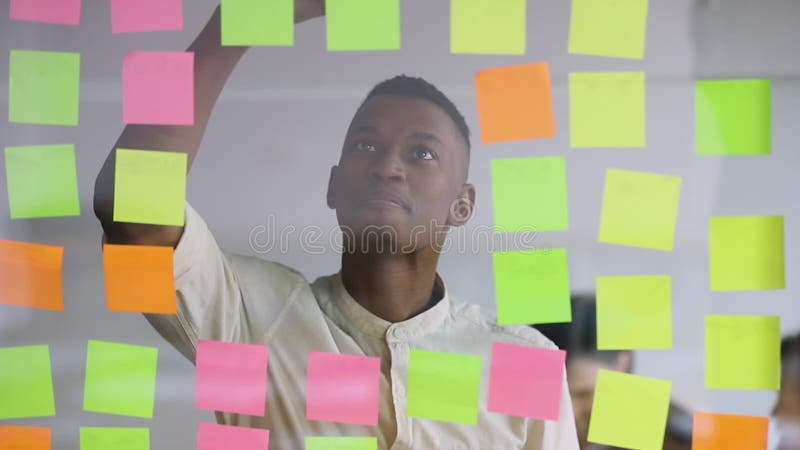 Jovem e bem-sucedido gerente africano sorridente satisfeito com o fluxo de trabalho do projeto.