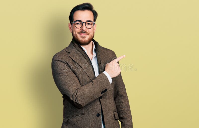 Young hispanic man wearing business jacket and glasses cheerful with a smile of face pointing with hand and finger up to the side with happy and natural expression on face. Young hispanic man wearing business jacket and glasses cheerful with a smile of face pointing with hand and finger up to the side with happy and natural expression on face