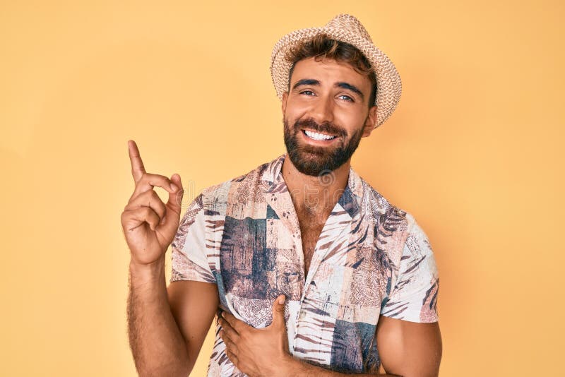 Young hispanic man wearing summer hat with a big smile on face, pointing with hand and finger to the side looking at the camera. Young hispanic man wearing summer hat with a big smile on face, pointing with hand and finger to the side looking at the camera