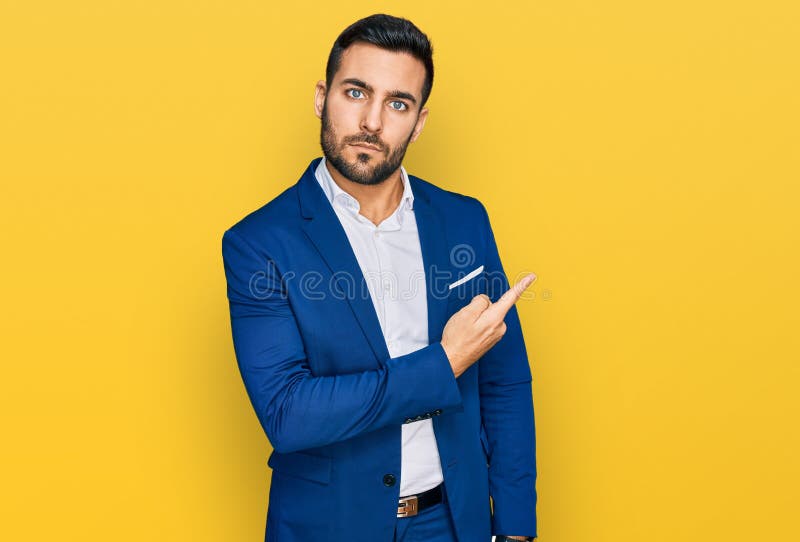 Young hispanic man wearing business jacket pointing with hand finger to the side showing advertisement, serious and calm face. Young hispanic man wearing business jacket pointing with hand finger to the side showing advertisement, serious and calm face