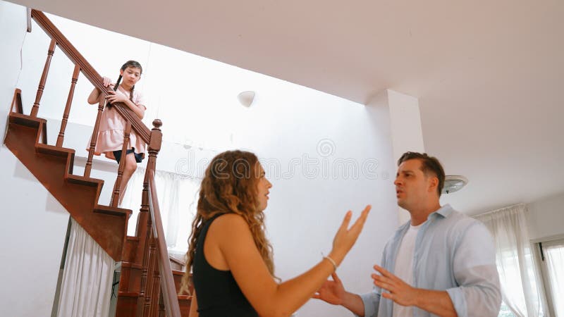 Stressed and unhappy young girl watch her parent arguing from the stair. Domestic violence at home and traumatic childhood develop to depression and anxiety. Unhealthy family concept. Synchronos. Stressed and unhappy young girl watch her parent arguing from the stair. Domestic violence at home and traumatic childhood develop to depression and anxiety. Unhealthy family concept. Synchronos