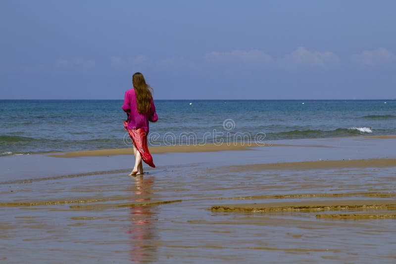 Lady in bright elegant red dress at beach, with sea and blue sky as background. Lady in bright elegant red dress at beach, with sea and blue sky as background.